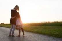 a mother and daughter hugging outdoors 