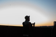 Silhouette of a man using an iphone outside at sunrise.