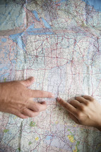 two fingers pointing to a location on a map. 