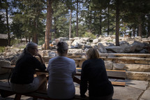 women sitting at a picnic table discussing scripture 