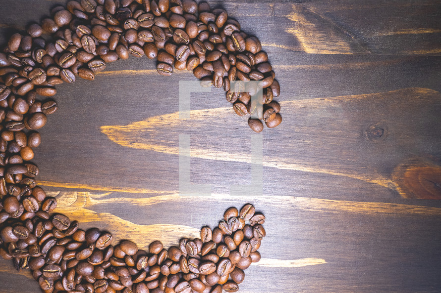 Coffee beans shaped in the letter C on a wooden background. Decorative banner for coffee products.