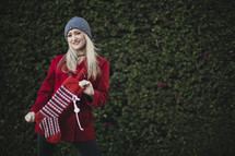 a woman holding a Christmas stocking outdoors 