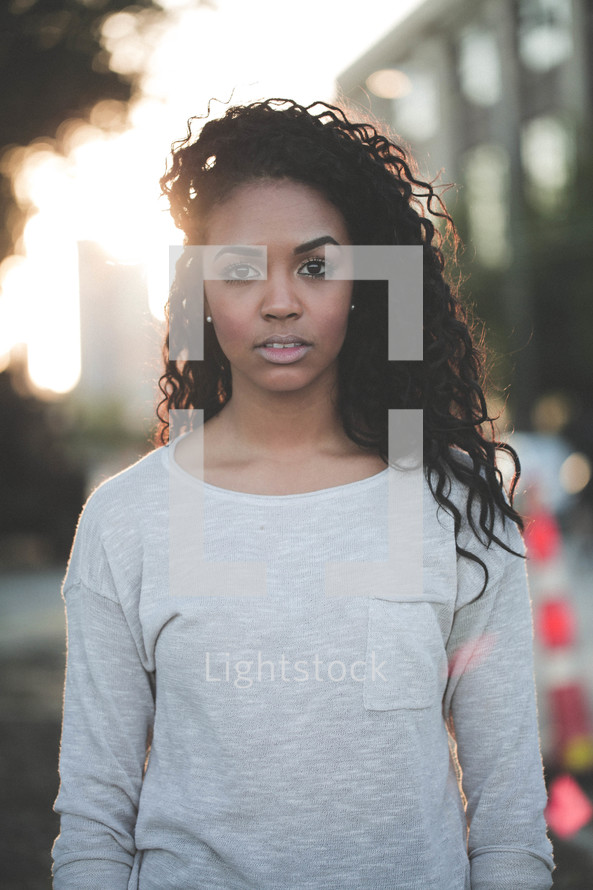 a young african-american woman standing under intense sunlight outdoors 