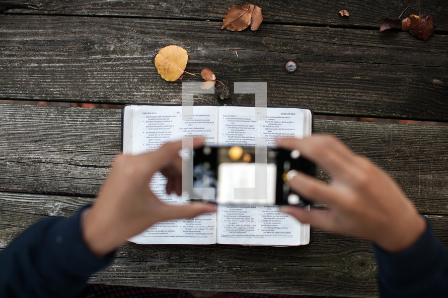 man taking a picture of Bible scripture with his cellphone 