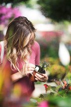 a woman picking out plants in a garden center 