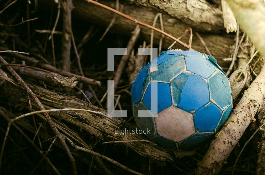 old soccer ball in a pile of sticks 