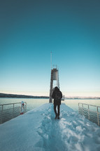 a man walking on a snow covered pier 