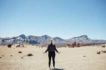 woman standing in a desert with open arms 