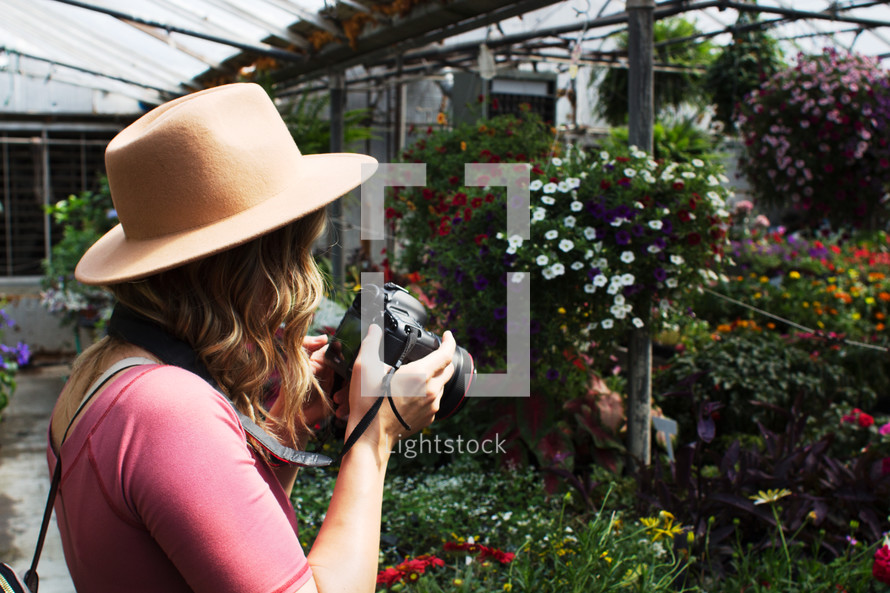 a young woman talking pictures of flowers in a greenhouse 