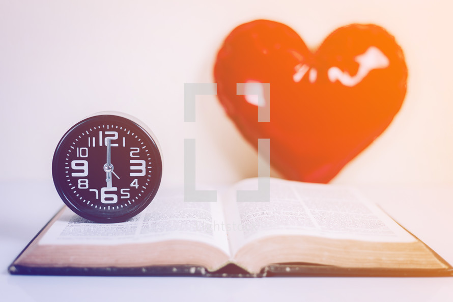 wall clock on an open Bible with a heart 