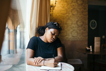 A woman sitting at a table writing in a journal 