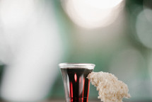 communion wine in a cup and bread on bokeh background 