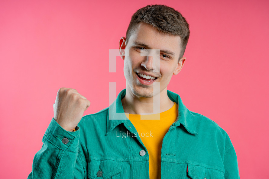 Handsome man shows triumph yes YEAH gesture of victory, he achieved result, goals. Guy glad, happy, surprised excited happy lady on pink background. Jackpot concept. High quality