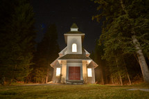 rural church surrounded by a pine forest at night 