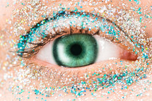 Macro female, green eye with glitter eye shadow, colorful sparks, crystals. Beauty background, fashion glamour makeup concept.

