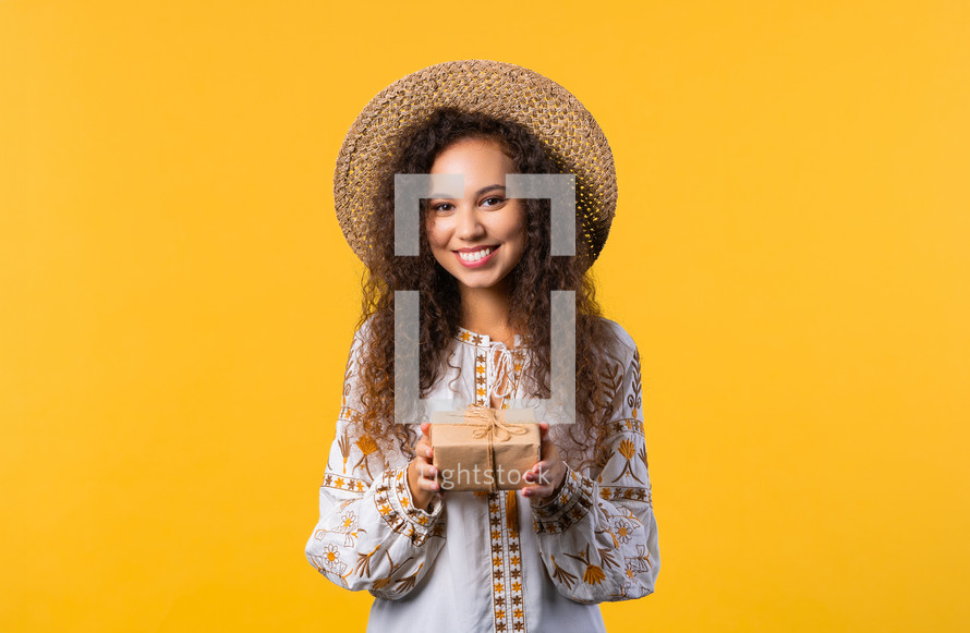 Ukrainian woman blonde hair with gift box on yellow background. Girl smiling, she is happy with present. High quality photo