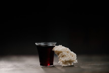 communion wine in a cup and bread on black background 