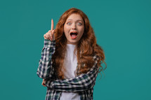 Happy stylish woman having idea eureka moment, pointing finger up on blue background. Clever lady showing answer gesture or remembered what she forgot, memory concept. High quality