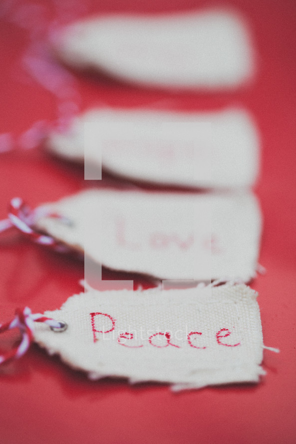 Christmas gift tags, the first one reading "Peace," on a red background.