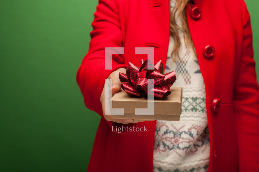 a woman in a red coat holding a Christmas gift 