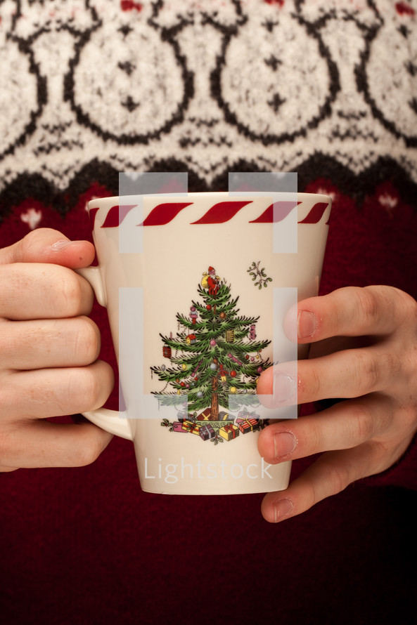 a man in a sweater holding a Christmas mug 