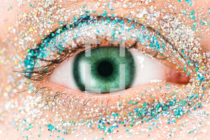 Macro female, green eye with glitter eye shadow, colorful sparks, crystals. Beauty background, fashion glamour makeup concept.
