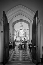 view through open doors of a woman sitting in an empty church 