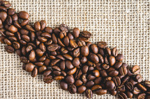 Bunch of Coffee beans laying on burlap fabric. Background voor coffee related products.