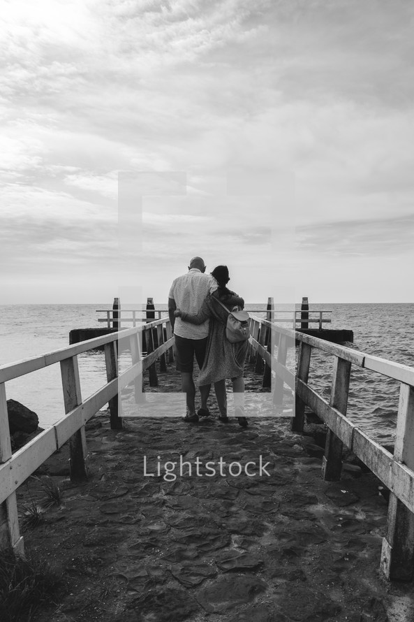 a couple walking down a pier 