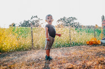 Happy adorable toddler boy having fun under rain. Baby laughs, he is very glad weather. High quality photo