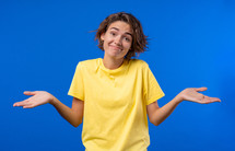 Confused pretty woman, shoulders up - can't help, makes gesture of I dont know. Difficult question, guilty reaction, puzzled stylish woman on blue background. High quality
