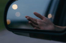 image of a hand in a rearview mirror 