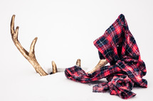 gold deer antlers in snow and a plaid scarf 