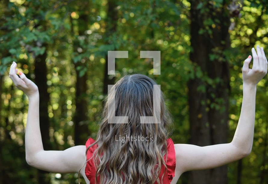 teen girl with arms raised standing in nature 