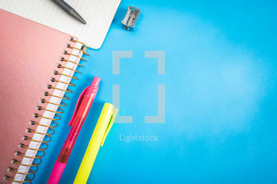 Different kind of school/office supplies for studying, on a blue background. Back to school.