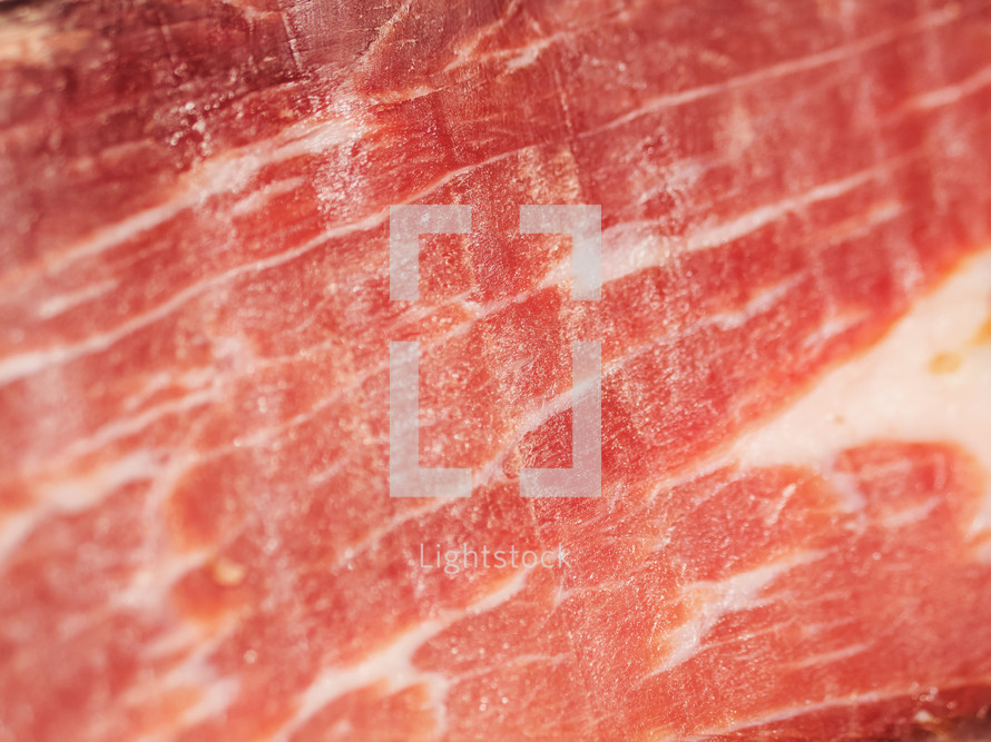 Jamon serrano. Traditional Spanish ham in the market close up. Pork leg ham on table. Meat in restaurant interior. Whole jamon on stand. Selective focus. Gourmet ham. Shallow DOF. Copy space.