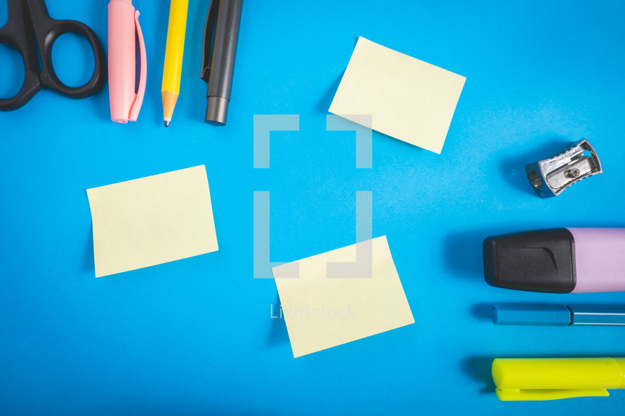 Different kind of school/office supplies for studying, on a blue background. Back to school.