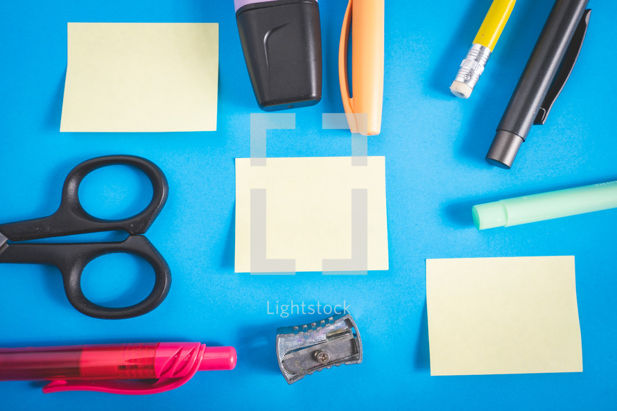 Different kind of school/office supplies for studying, on a blue background. Back to school.