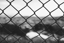 View of the countryside through a chain link fence.