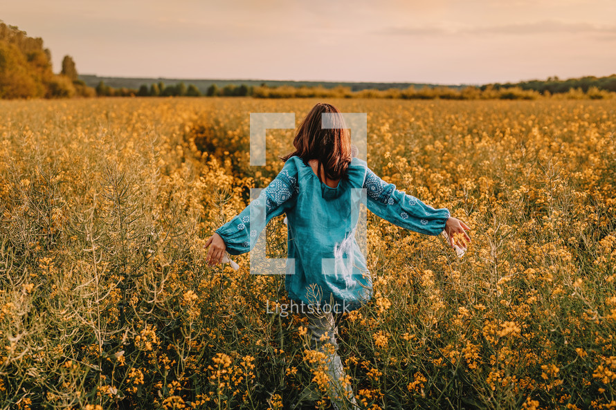 Ukrainian woman in yellow rapeseed field. Young lady in blue embroidery vyshyvanka blouse. Ukraine, independence, freedom, patriot symbol, victory in war.