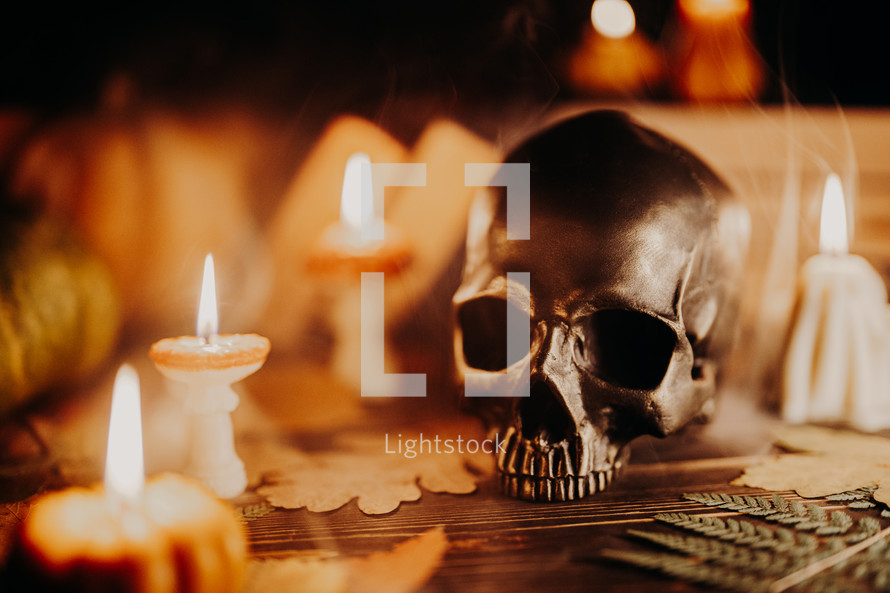 Mystique background - bronze human skull with candle. Visual gothic aesthetic. Autumn pumpkin candle, falling leaves. Ambience of fall. Seasonal promotions or dramatic visual storytelling.