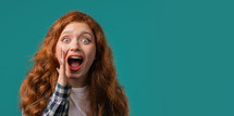 Attention, portrait of red haired young woman shouting, holding hand near open mouth isolated on blue background with copy space for your advertisement. High quality photo