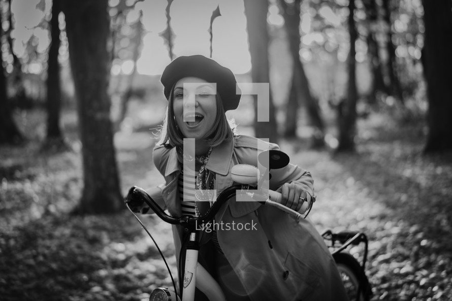 Beautiful dreamy portrait of young smiling woman in french beret cycling alone in park. Sunny day in forest. Trendy lady on vintage bicycle, healthy lifestyle, aesthetic scene. High quality photo