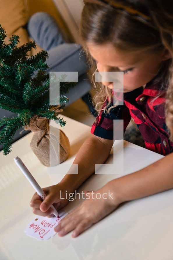 child addressing a gift tag to mom 
