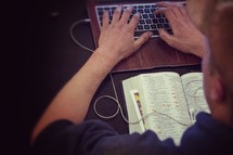 man typing on a keyboard and an open Bible 