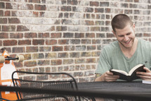 man reading a Bible outdoors at a table