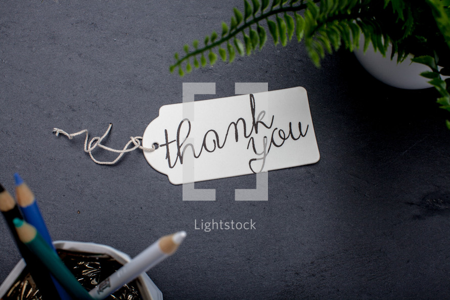 words thank you on a gift tag on a desk 