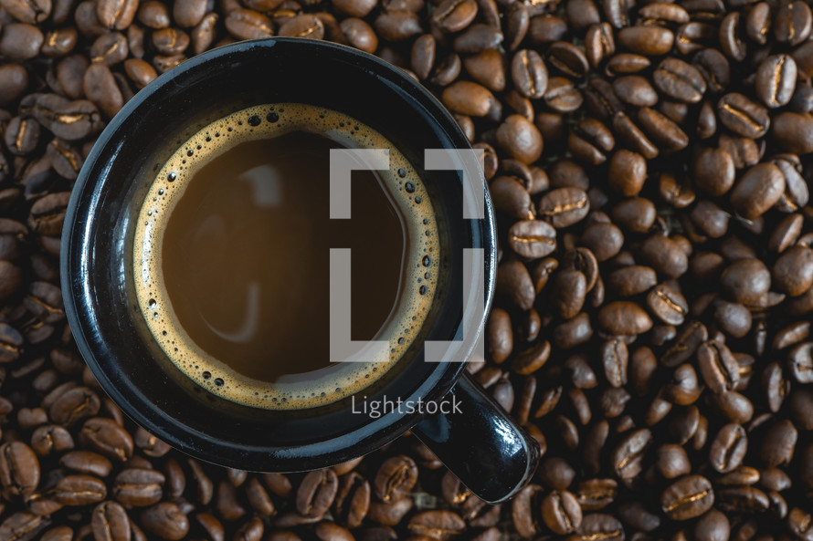 A fresh cup of coffee on a background of coffee beans.