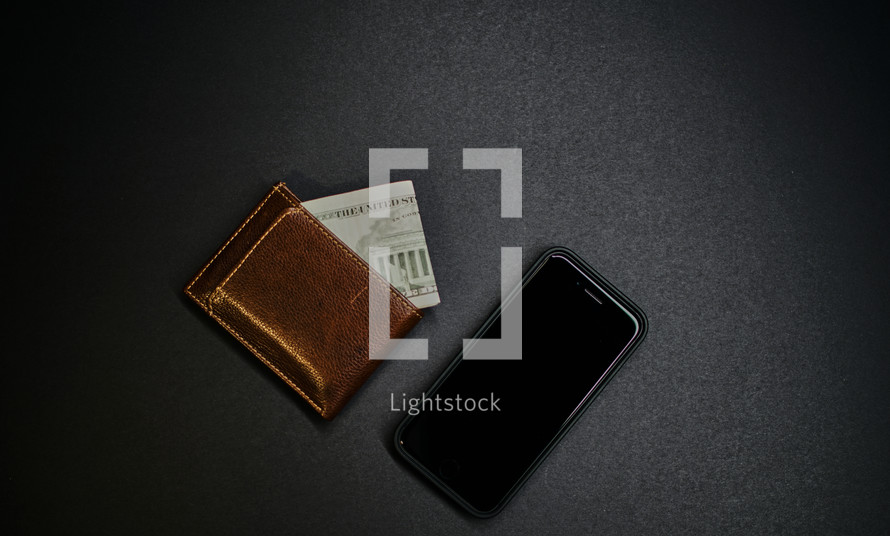 Brown leather wallet next to a cell phone.