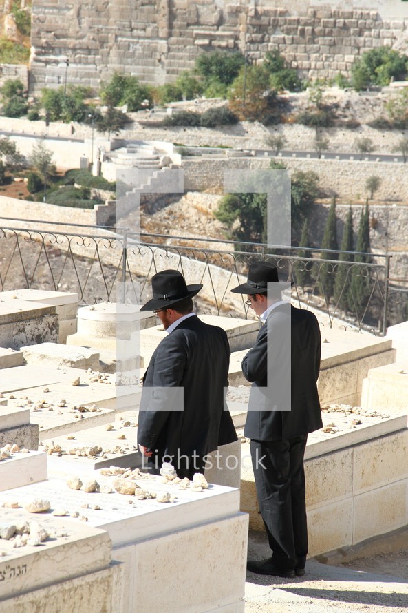 Jewish men leaving stones at a loved ones' grave on the Mount of Olives 